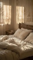 Cozy bedroom with vintage lace curtains filtering warm sunlight, creating romantic shadows on unmade bed with white linens and wooden headboard.