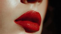 Close-up of woman's glossy red lips with rich crimson lipstick, sensual beauty makeup for cosmetics and fashion advertising campaigns.