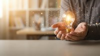 Businessman holding glowing light bulb with network connections representing innovation, creativity and bright ideas in modern office environment.