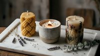 Handmade candles with lavender and eucalyptus botanicals arranged on white tray, featuring beeswax twisted pillar, concrete vessel, and herb-embedded design for home decor and wellness.