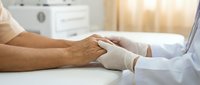 Medical professional in white gloves examining patient's arm during healthcare consultation in bright clinical setting for diagnostic purposes.