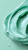 Swirling mint green cosmetic cream texture with water droplets and pearly shimmer effect on pastel background, macro photography for skincare products.