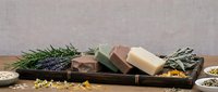 Natural handmade soap bars with lavender and herbs on wooden tray, organic skincare products for spa and wellness routines.