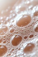 Macro photography of water droplets on brown surface creating abstract pattern with bokeh effect and light reflections. Natural phenomenon showing surface tension.