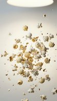 Fresh popped popcorn kernels falling and floating in mid-air against clean white background for snack food advertising and kitchen concepts.