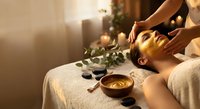 Young Asian woman receiving relaxing head massage at luxury spa with hot stones, candles and warm lighting for wellness and self-care treatments.