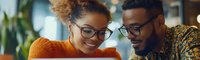 Young African American couple sharing joyful moment while looking at mobile phone screen, wearing glasses and stylish casual attire in modern cafe setting.
