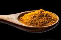 Ground turmeric powder in wooden spoon against black background, bright yellow organic spice used in Asian cuisine and natural medicine.