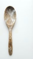 Rustic wooden spoon dusted with flour on white background for baking and cooking projects.
