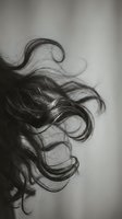 Flowing dark hair strands in motion captured in artistic black and white photography with soft focus and elegant movement for beauty and fashion concepts.