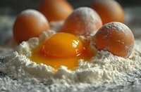 Fresh egg yolk surrounded by flour with whole eggs in background, ready for homemade pasta or baking preparation.
