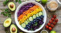 Colorful rainbow salad bowl with fresh vegetables, avocado, blueberries and quinoa on rustic wooden background. Healthy eating and clean nutrition concept.