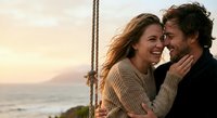 Happy couple embracing on sailboat at sunset, romantic moment during ocean voyage, love and adventure lifestyle, warm golden hour lighting on deck.