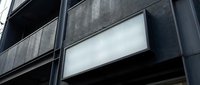 Modern blank white signage on dark building facade for business branding and advertising display mockup.