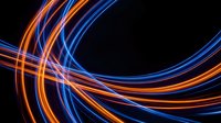 Dynamic light trails in orange and blue creating flowing curves on black background for modern digital design and technology concepts.