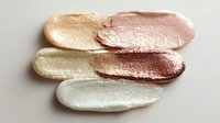 Metallic makeup swatches in gold, rose gold, copper, and pearl tones on white background, showcasing luxury cosmetic textures for beauty industry use.