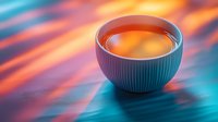 Ceramic bowl with hot tea on vibrant turquoise and orange background with motion blur effect creates modern minimalist composition for food and beverage marketing.