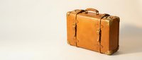 Vintage brown leather suitcase with brass corners and buckles on neutral background for travel and retro design concepts.