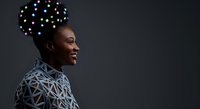 Smiling African American man in profile wearing geometric patterned shirt with glowing digital nodes floating above head representing artificial intelligence and neural networks.