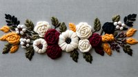 Elegant floral arrangement with felt roses, pumpkins and autumn leaves in burgundy, white, and orange on gray linen background, handcrafted textile art piece.