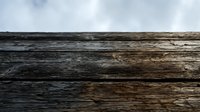 Weathered wooden planks with natural grain texture against cloudy sky background for rustic design projects and outdoor construction themes.