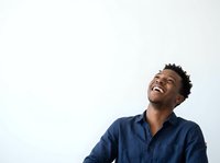 Young African American man wearing a dark navy button-up shirt, smiling and looking upward against a white background. Suitable for corporate, lifestyle, and motivational content.