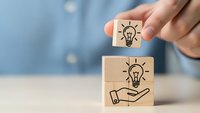 Hand stacking wooden blocks with lightbulb icons representing creative ideas, innovation and business solution concepts for brainstorming sessions.