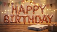 Rose gold foil balloons spelling Happy Birthday on a wooden table with bokeh string lights and colorful bunting in the background.