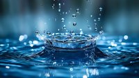 Macro photography of water drop impact creating crown splash formation with flying droplets on blue surface, frozen motion capture showing liquid dynamics and ripples.