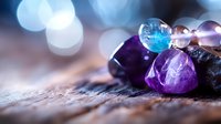 Colorful healing crystals and gemstones with amethyst and blue agate on rustic wooden surface against soft bokeh background, spiritual wellness concept.