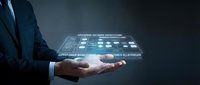 Professional businessman in dark suit holding futuristic holographic interface with digital data visualization and technology elements on dark background.