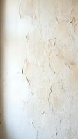 Weathered white wall with peeling paint and cracks showing aged texture for vintage interior design backgrounds and renovation projects.