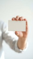 Hand holding blank business card against white background with natural lighting and shadow. Isolated mockup for corporate branding and design.