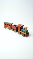 Vintage wooden toy train set with locomotive, tender, and passenger car featuring red, blue, and yellow painted details on white background.