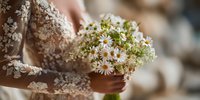 Woman in lace dress holding delicate white wildflower bouquet with small blooms for wedding ceremony or romantic occasion.