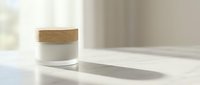 Cosmetic jar with wooden lid on white surface, casting shadow in bright natural light, suitable for skincare and beauty product packaging design.