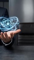 Businessman in dark suit holding glowing digital security hologram with padlock and gears icon, representing cybersecurity, data protection, and verified network systems for enterprise solutions.