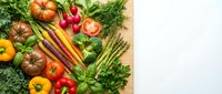 Fresh organic vegetables and herbs arranged on wooden cutting board including tomatoes, carrots, peppers, asparagus and leafy greens for healthy cooking.