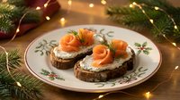 Festive smoked salmon appetizers on dark bread with cream cheese and dill garnish served on elegant plate with Christmas lights and pine branches.