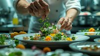 Professional chef garnishing an elegant seafood dish with fresh microgreens and edible flowers in upscale restaurant kitchen. Fine dining plating technique captured in atmospheric lighting.