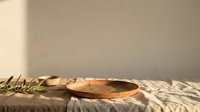 Wooden bowl with olive branch on neutral linen fabric, warm natural lighting casting shadows, suitable for food styling, culinary blogs, restaurant menus, wellness content.