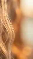 Close-up of blonde hair strands with warm golden sunlight creating soft bokeh background for beauty and haircare concepts.