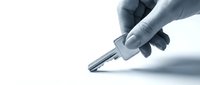 Hand holding a silver key on white background, symbolizing access, security, real estate, and new beginnings in business and property concepts.