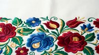 Traditional Hungarian folk embroidery with colorful floral motifs featuring roses and decorative elements on white fabric for cultural textile design projects.