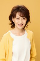 Asian woman with short layered hair wearing yellow cardigan and white top smiling warmly against yellow background, portrait orientation for lifestyle and fashion content.