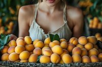 Young Caucasian woman in white summer dress holding fresh ripe apricots in rustic basket against blurred garden background, organic harvest concept.