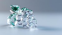 Crystal glass grape cluster with emerald green leaves on soft gray background, elegant decorative accent piece showcasing fine craftsmanship and delicate detail.