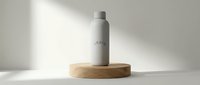 Stainless steel water bottle with gray finish sitting on wooden circular base against white background with natural lighting.