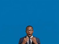 Surprised African American male professional wearing glasses and dark business suit with tie, expressing shock or excitement against solid blue background for corporate and business communications.