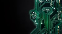 Green circuit board with intricate electronic pathways and components on dark background for technology and digital innovation projects.